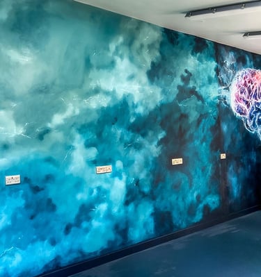Angled view on mural with teal stormy clouds and a bit of stylised brain in pink and teal colours. 