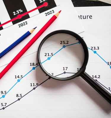 magnifying glass highlighting investing chart symbolizing gold market for precious metals