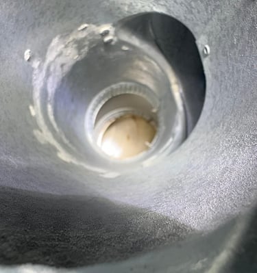 A view from inside a dirty and worn metal chimney flue, highlighting the need for a professional cleaning and inspection by R