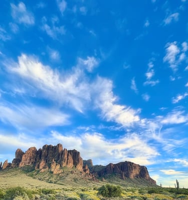 Rustic wooden fence overlooking the Superstition Mountains in the Arizona desert under a blue sky.