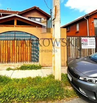 casa dos pisos color naranjo con puerta en forma de reja y cierre de cemento 