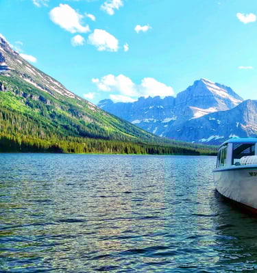The Morning Eagle tour boat docked on a scenic lake in Glacier National Park with mountain views.