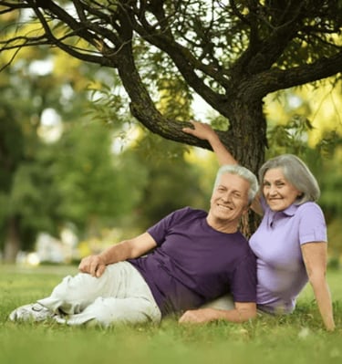 a old man and woman sitting on the grass