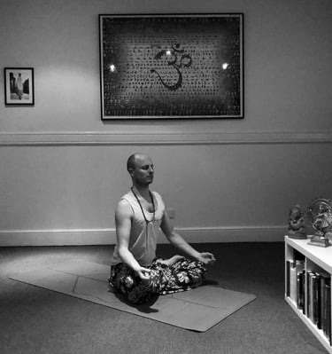 a man sitting meditating on a yoga mat in a room