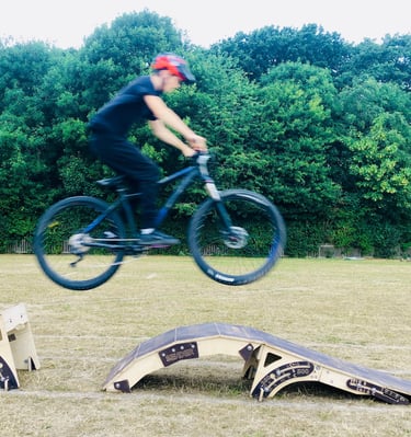 a man jumping a bicycle off some ramps in a field