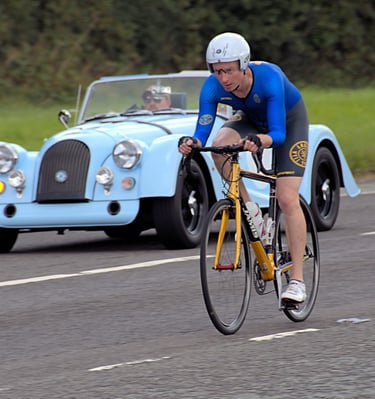 a man riding a bike with a car behind him
