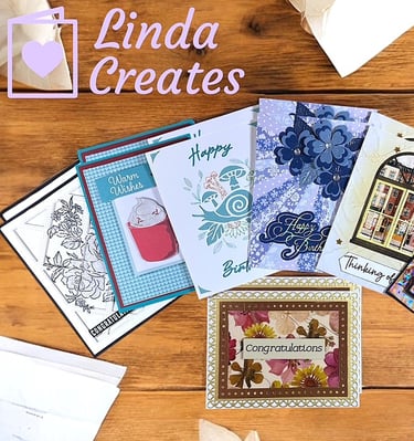 An array of handmade cards laying on a wooden desk.