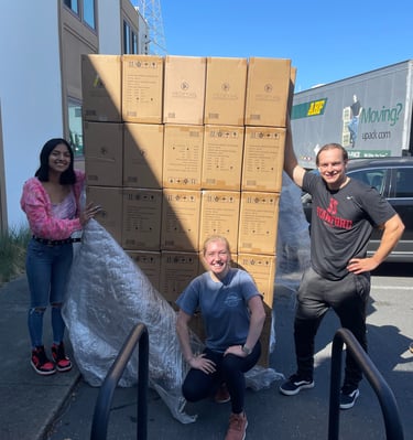 Three people with a large pallet of air purifiers in boxes