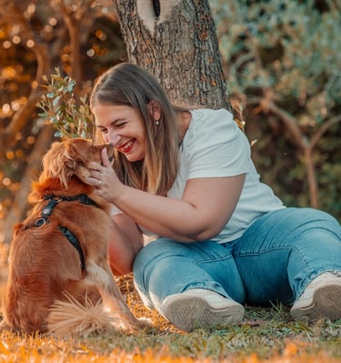 ragazza che sorride al proprio cucciolo seduta sotto un albero