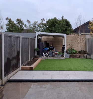 a backyard patio with a green lawn and a small garden