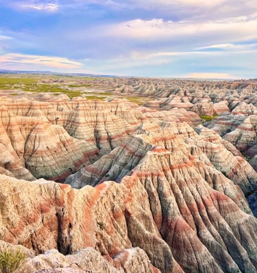 Vibrant layered rock formations and jagged ridges under a blue sky at Badlands National Park.