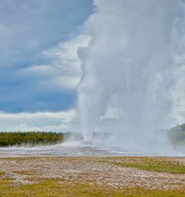 Old Faithful Geyser erupting with a massive steam column at Yellowstone National Park.
