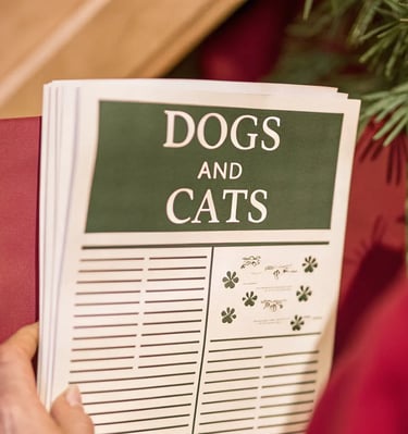 a person holding a book with a dog and cat