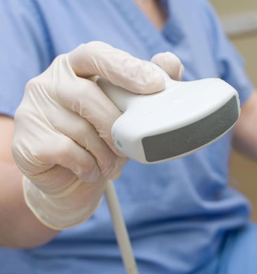 a person in a blue scrub suit and gloves holding a ultrasound tool