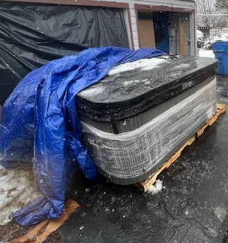 a hot tub in a driveway under a tarp