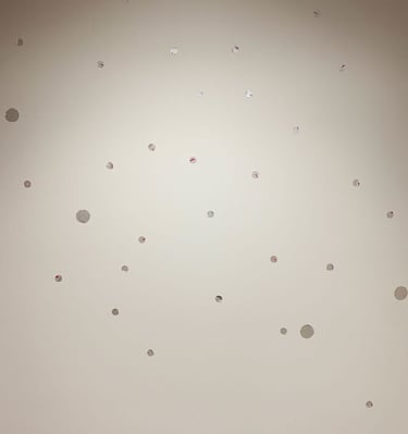 Small silver dot decals are scattered over a white wall, adding elegance with a playful touch.