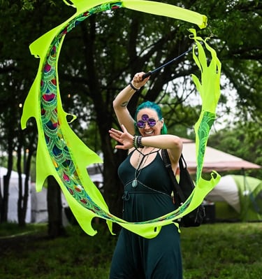 The creator of Anointistry is a woman in this photo dancing with a neon green dragon kite on s stick