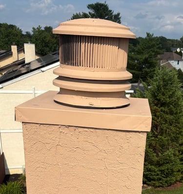 A newly waterproofed and resurfaced chimney with a modern round chimney cap, installed by Roslyn Chimney in Roslyn, New York