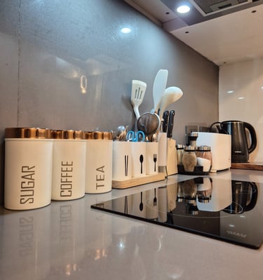 a kitchen counter top with a stove top, and other kitchen amenities like spoons, spatula, containers