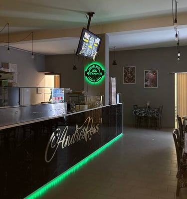 Bancone interno di AndrèsRosa Pizzeria ad Alseno con il logo visibile, ambiente accogliente e modern