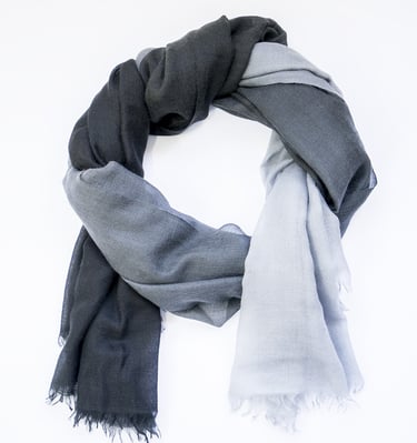 Elegant two-tone scarf with smooth black to grey gradient, styled in a soft circular wrap on white.