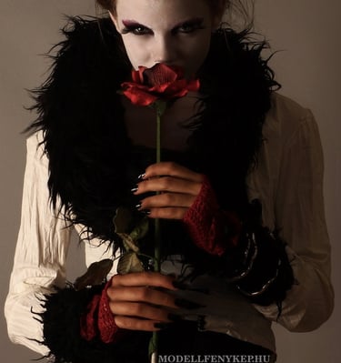 a beautiful woman with a white vampire face and black hair and a black feathered scarf