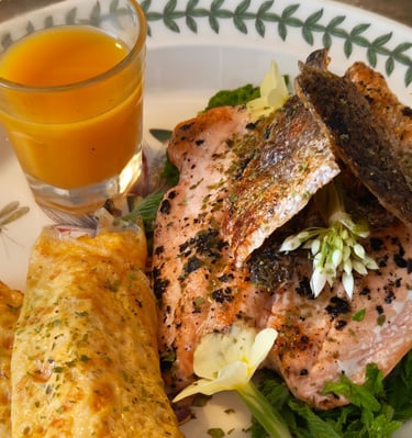 Rolled egg, salmon with crispy skin, wild garlic flower garnish, sea buckthorn juice