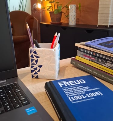 Mesa de trabalho com livros de autoras como Ana Suy, Gayle Rubin e Geni Núñez, ao lado do notebook u