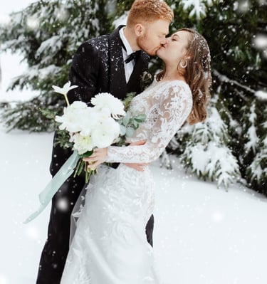 a bride and groom kissing in the snow