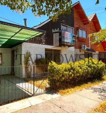 casa dividida color café con reja baja de acero y arbustos , estacionamiento tipo quincho