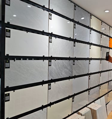 Showroom display of large format porcelain wall tiles with grey marble and stone patterns.