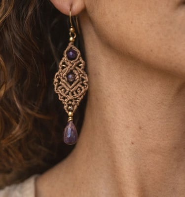 Aretes artesanales de macramé bohemio con piedras de amatista y nudos detallados.