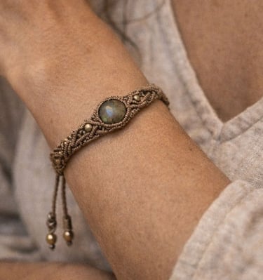 Pulsera artesanal de macramé bohemio con labradorita y cuentas de latón en muñeca femenina.