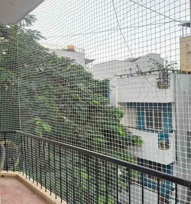 Evening view of a balcony with safety netting softly illuminated by warm indoor lights.