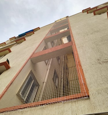 Wide shot showing multiple floors of a construction site protected by bright orange safety nets.