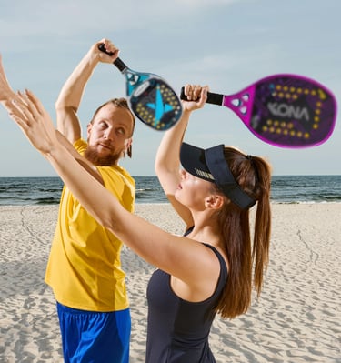 Professor corrigindo sua aluna de beach tennis em uma praia ensolarada.