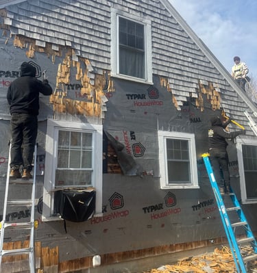 Professional contractors removing old cedar shingle siding from a house to install new exterior house wrap.