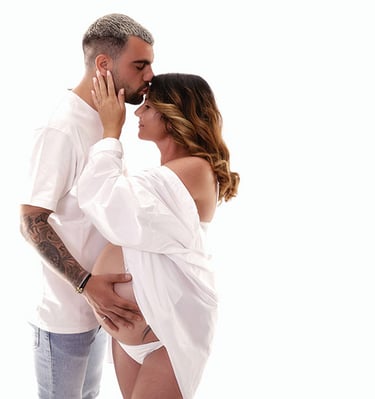 Un homme embrasse tendrement le front de sa compagne enceinte lors d’une séance photo de grossesse