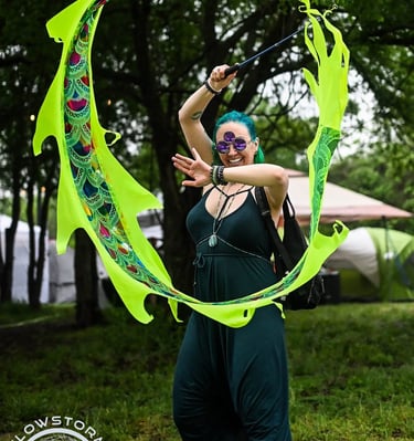 The creator of Anointistry is a woman in this photo dancing with a neon green dragon kite on s stick