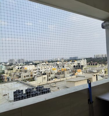 Installation team fitting pigeon nets on a large sarja window in Marathahalli.