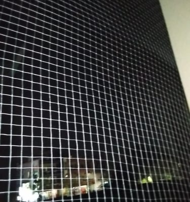 Installation process of anti-pigeon nets by Arjilli Enterrises team on a window frame.