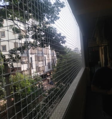 Hands of a technician from Arjilli Enterprises fixing an anti pigeon net on a railing.