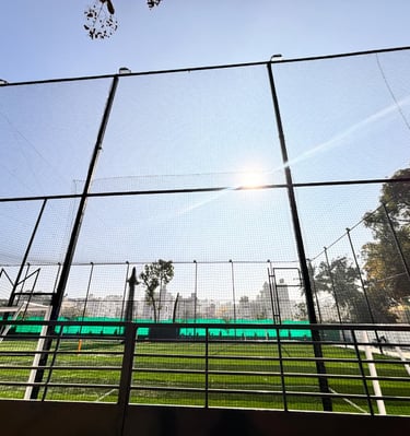A cricket net setup on a sunny Chennai playground with players practicing.