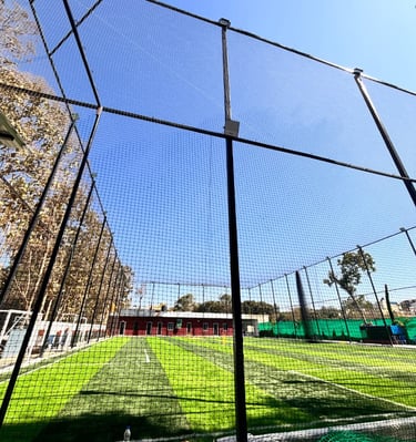 Technician securing a sports net tightly on metal poles under bright Chennai sunlight.