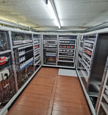 Industrial electrical control panels with circuit breakers and wiring in a power distribution room.