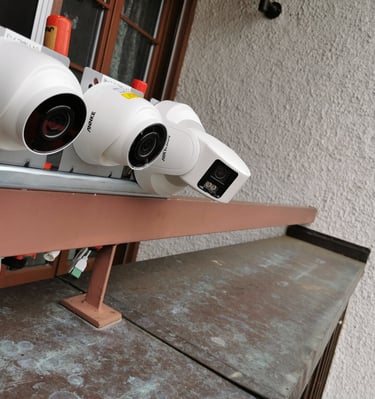 Multiple outdoor security cameras including Annke and Hikvision brands mounted on an exterior wall.