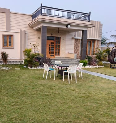 Modern luxury PG exterior featuring a green lawn, patio furniture, and balcony railing.