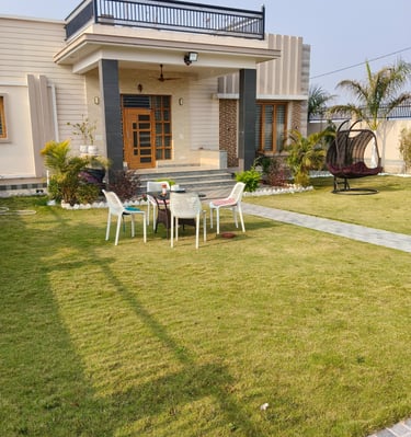 Modern luxury PG exterior with a spacious green lawn, patio furniture, and hanging swing chair.