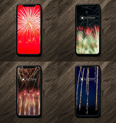 a group of four cell phones with fireworks in the background