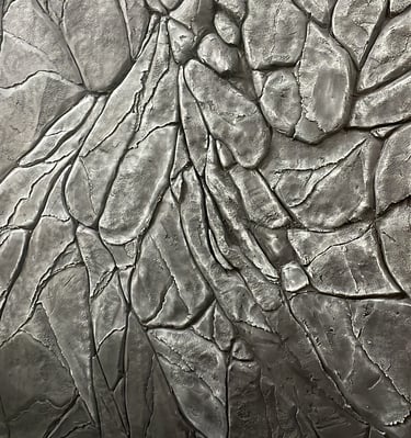 Textured decorative concrete wall with a realistic dark grey faux stone and rock cliff face finish.